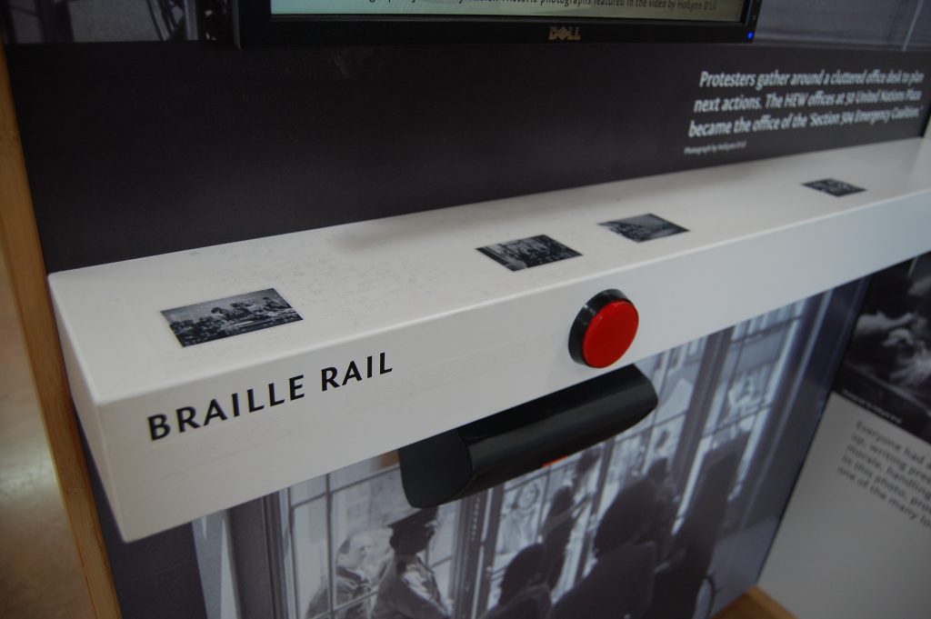 Braille rail detail with red button to activate the video
